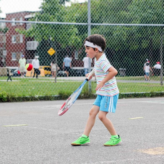A boy playing tennis in an outdoor tennis court