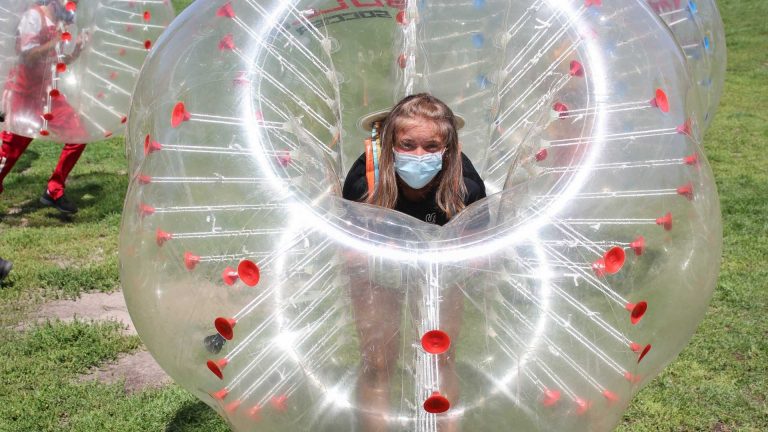 A young girl inside of an inflatable balloon that has red dots representing COVID-19