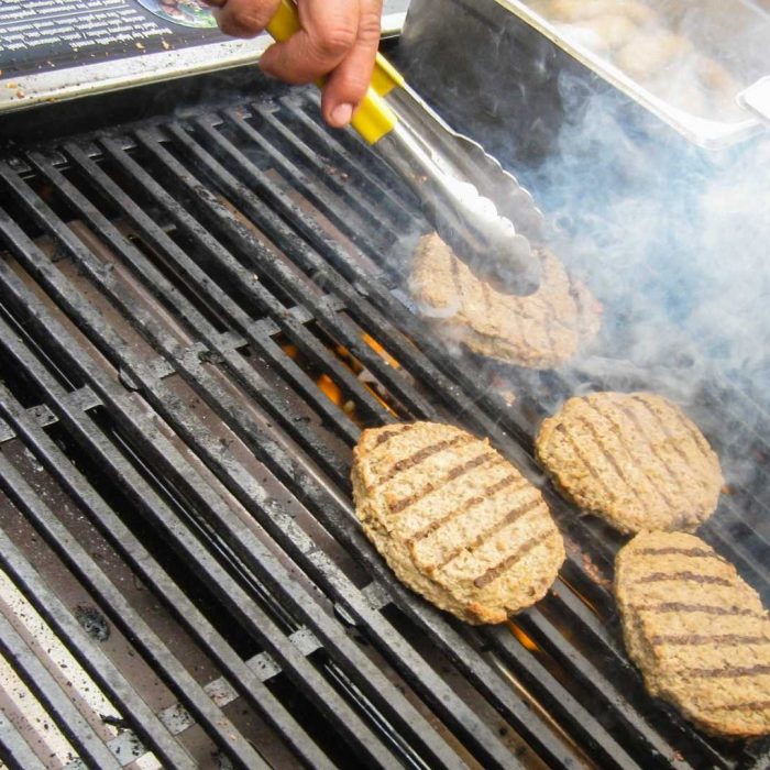 Four burger patties are being grilled