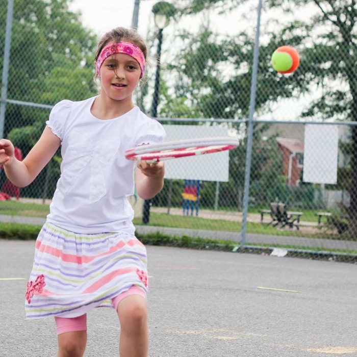 A girl playing tennis in an outdoor tennis court