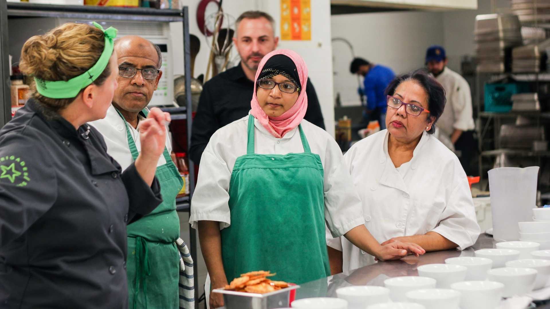 A group of adult listening to their instructor inside the kitchen