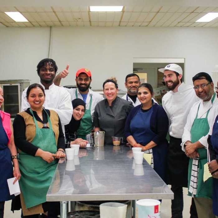 A group of adults gathered in the kitchen for their cooking lesson